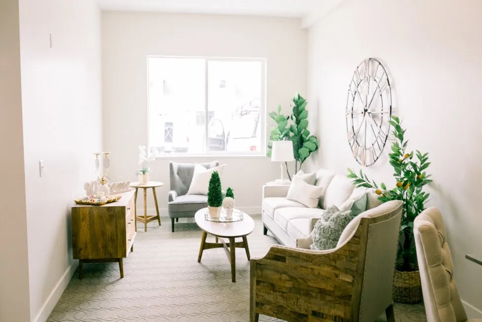 A bright community sitting room with soft seating and greenery