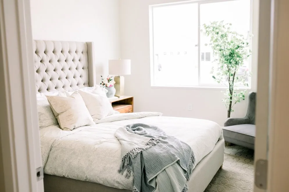 A private suite bedroom with a tufted headboard and soft natural light